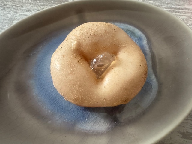 おさらのうえにのった、もっちゅりんのこくとうあんどわらびもちの写真。ドーナツはしろっぽくてグレーズがかかっていますが、穴の部分にわらびもちのような透明なものがのっています。ほかのものもそうですが、特にこれわ手につきやすいので、お手ふき必須でした
