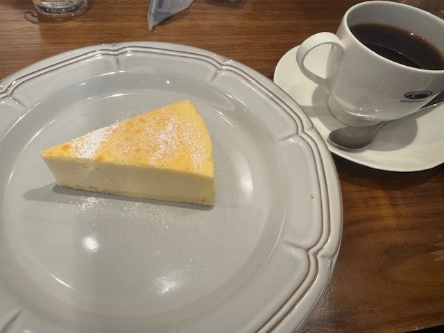 テーブルのうえのしろくて大きなおさらにのったベイクドチーズケーキと、ソーサーにハイッタコーヒーの写真