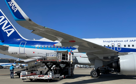 コンテナを航空機内の貨物室に運搬する特殊車両の写真です