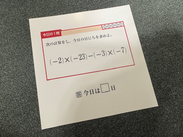 ひめくりの一枚をうつした写真。カードにわ今日のいちもん。次の計算をし、今日の日にちをもとめよ。とかかれたしたに1枚ずつ異なる数式がかかれています。これを解くと今日がなんにちかわかるようになっています。答え、きょうわシカクにちとかかれたシカクのところに回答がハイります