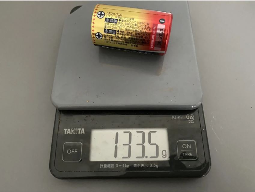 クッキングスケールでたんいちの乾電池ひとつの重さをはかると１３３．５グラムと表示されている様子
