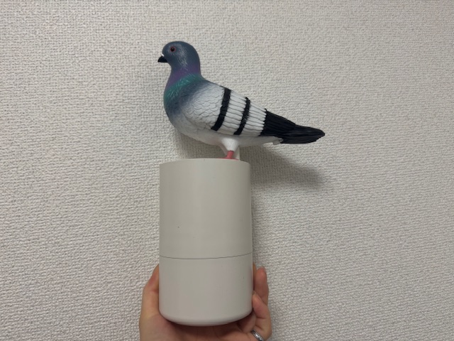 鳩のハンドディスペンサーの全体をうつした写真。ホワイトのスタイリッシュなディスペンサーのうえに鳩のもけいが乗っている写真。鳩は野生の鳩そっくりのカラーリングで羽の感じまでリアルに再現されています