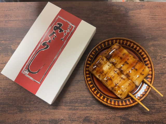 大阪のいたみくうこうで購入した、きやすのみたらし団子の紙製のハコと、ちゃいろいお皿ににほんのせたみたらしだんごの写真。やきめがついたおだんごにみたらしがたっぷりからまっていておいしそうです