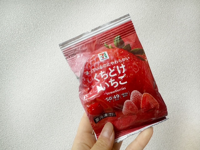くちどけいちごのパッケージを手で持った写真。ぜんたいがあかっぽいふくろで、中央に白い文字でくちどけいちごと書かれており、背景にはいちごの写真がのっています