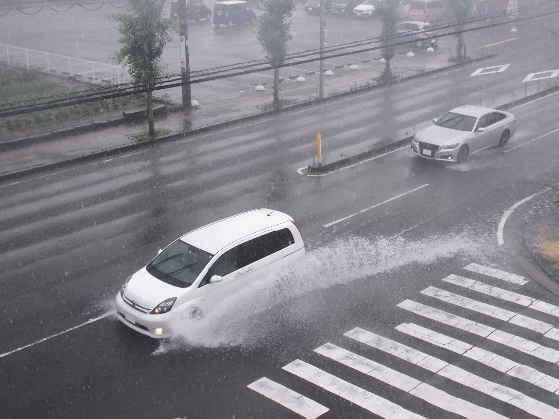 ゲリラ豪雨で冠水した道路を走るくるまの写真