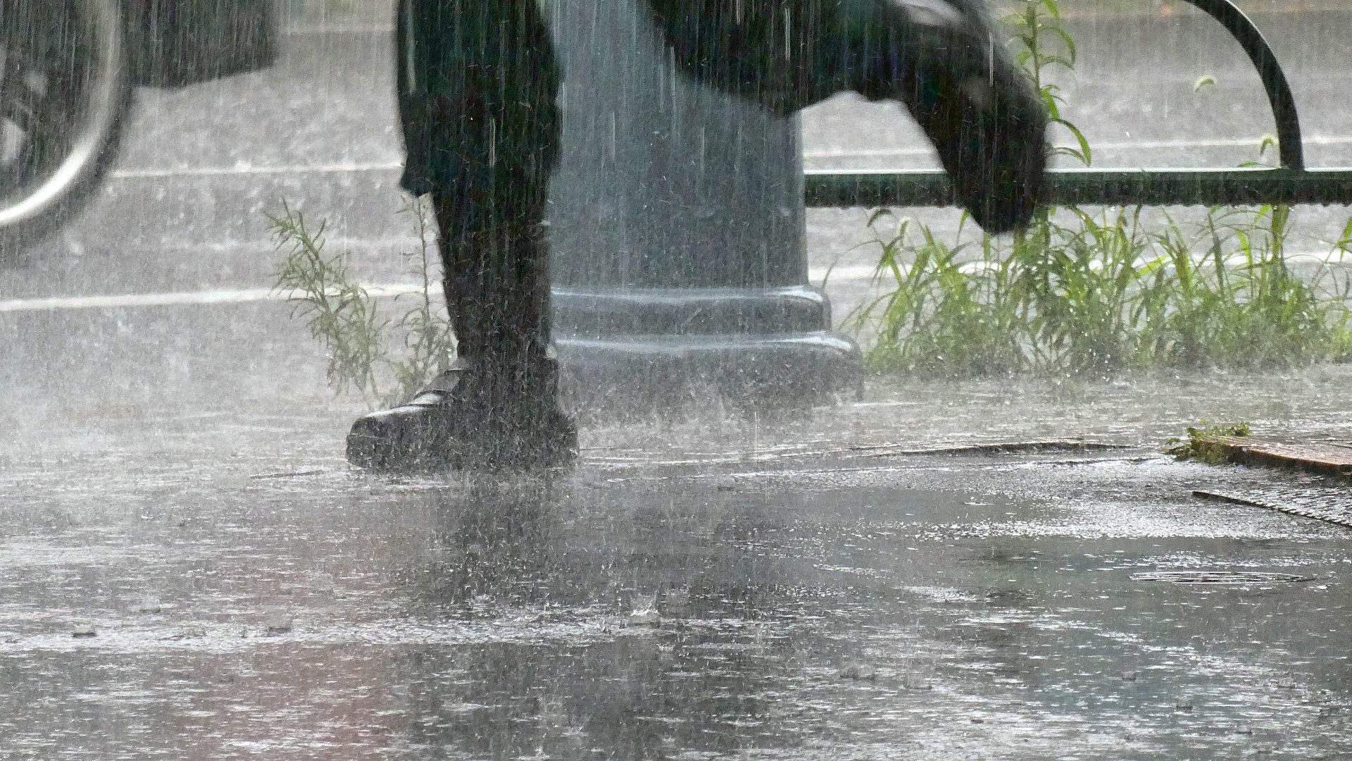 ゲリラ雷雨の中、歩道を歩いている男性の足元が映っている写真です。靴もズボンもずぶぬれの様子です