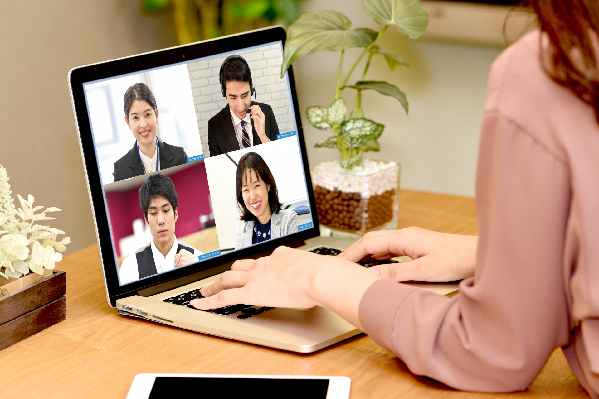 自宅でオンライン会議をする女性の写真。パソコンの画面上には男女よにんの顔が映し出されています