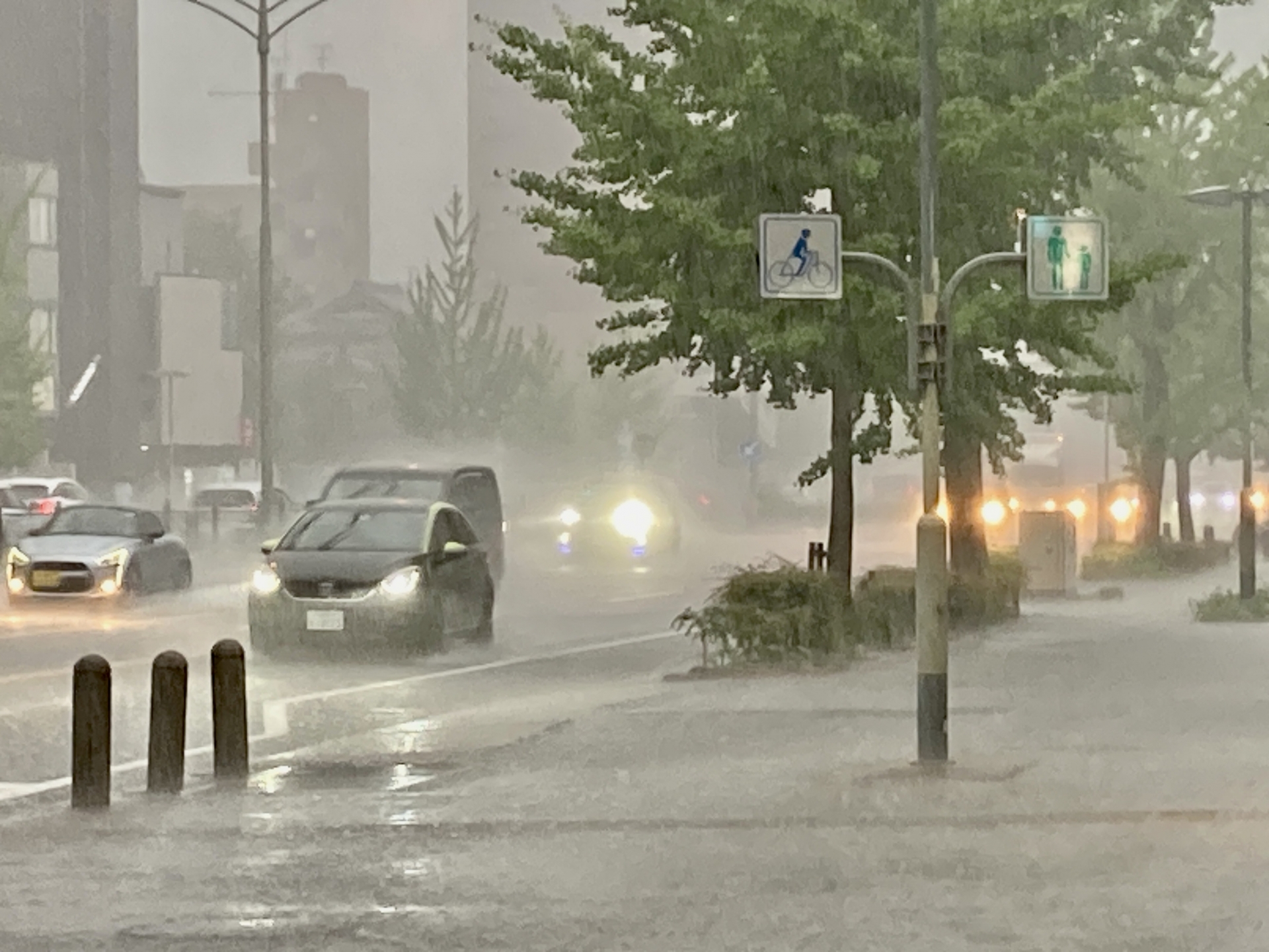 ゲリラ豪雨にみまわれたまちのなかを走る自動車の写真です