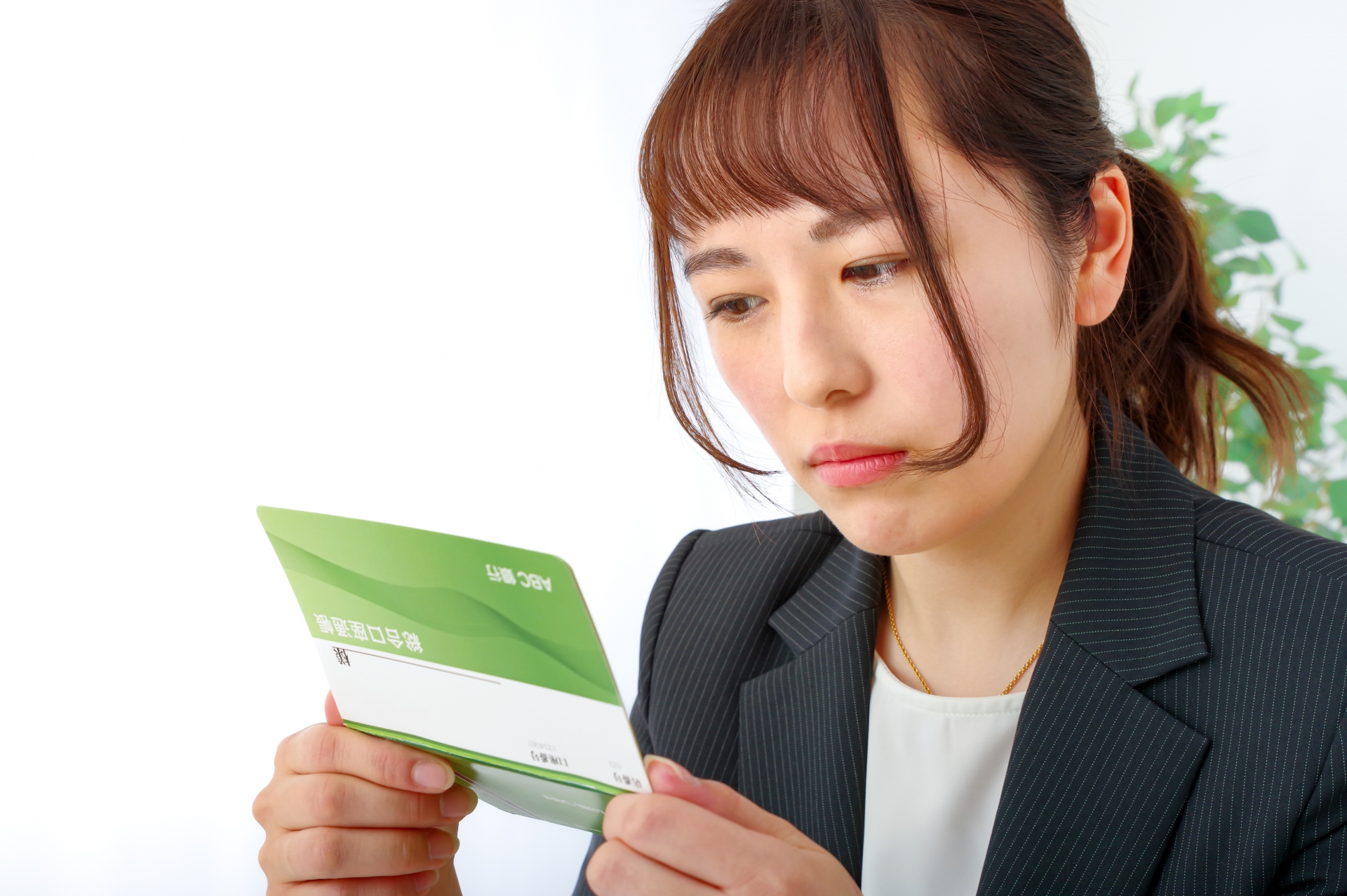 貯金通帳をみながら憂鬱な表情を浮かべる女性