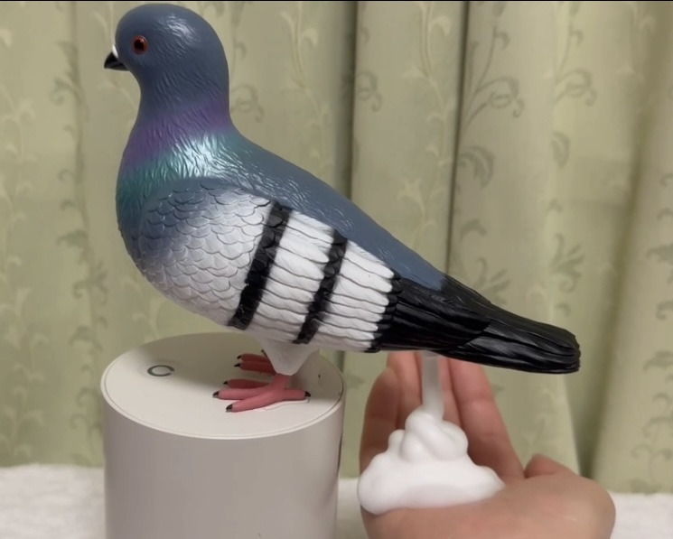 かざした手に、鳩のおしりからハンドソープが出てくる様子を写した写真