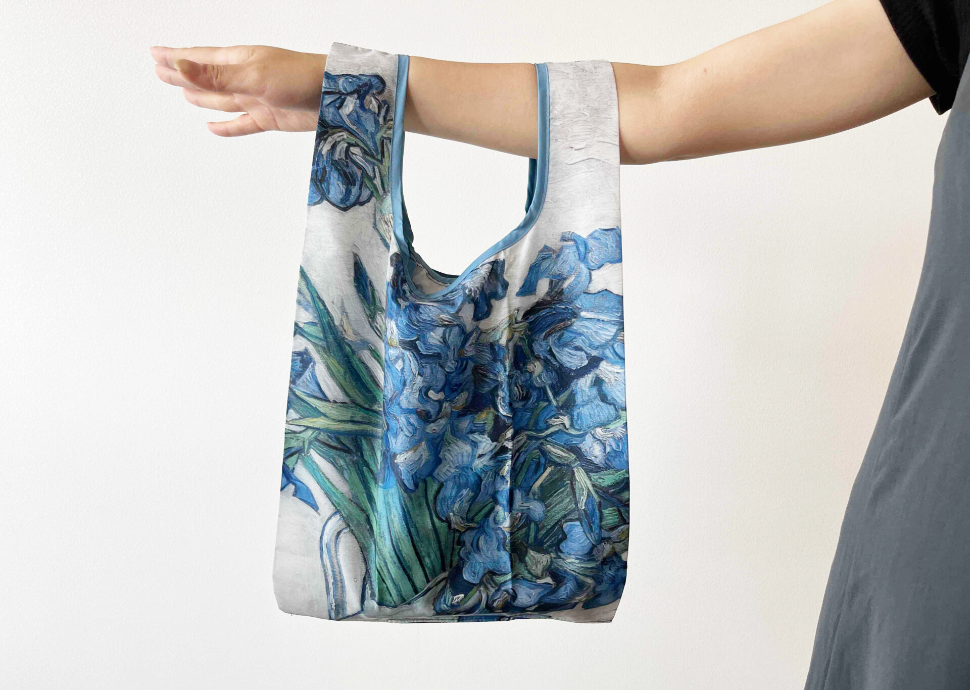 ゴッホのアイリスがデザインされたポケッタブルバッグをてにかけている写真。全体てきにあおっぽいカラーリングです