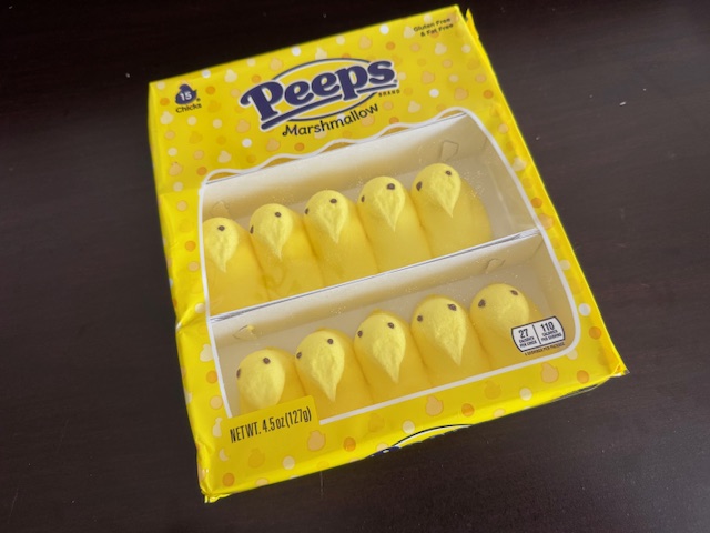 イエローのピープスのパッケージの写真。きいろくてしかくいプラスチックのふくろに、よこに6個ずつならんだ、イエローのひよこがたのマシュマロ。これがさんれつハイってひとつのパッケージにハイっています。日本のお菓子にたとえるなら、おみやげでゆうめいな、あのひよこのような立体てきなかたち。そんな形状のイエローのマシュマロにちゃいろいめがふたつ描かれていますが、ところどころずれていたりして、手作りのようなあじわいがあってかわいいひよこです