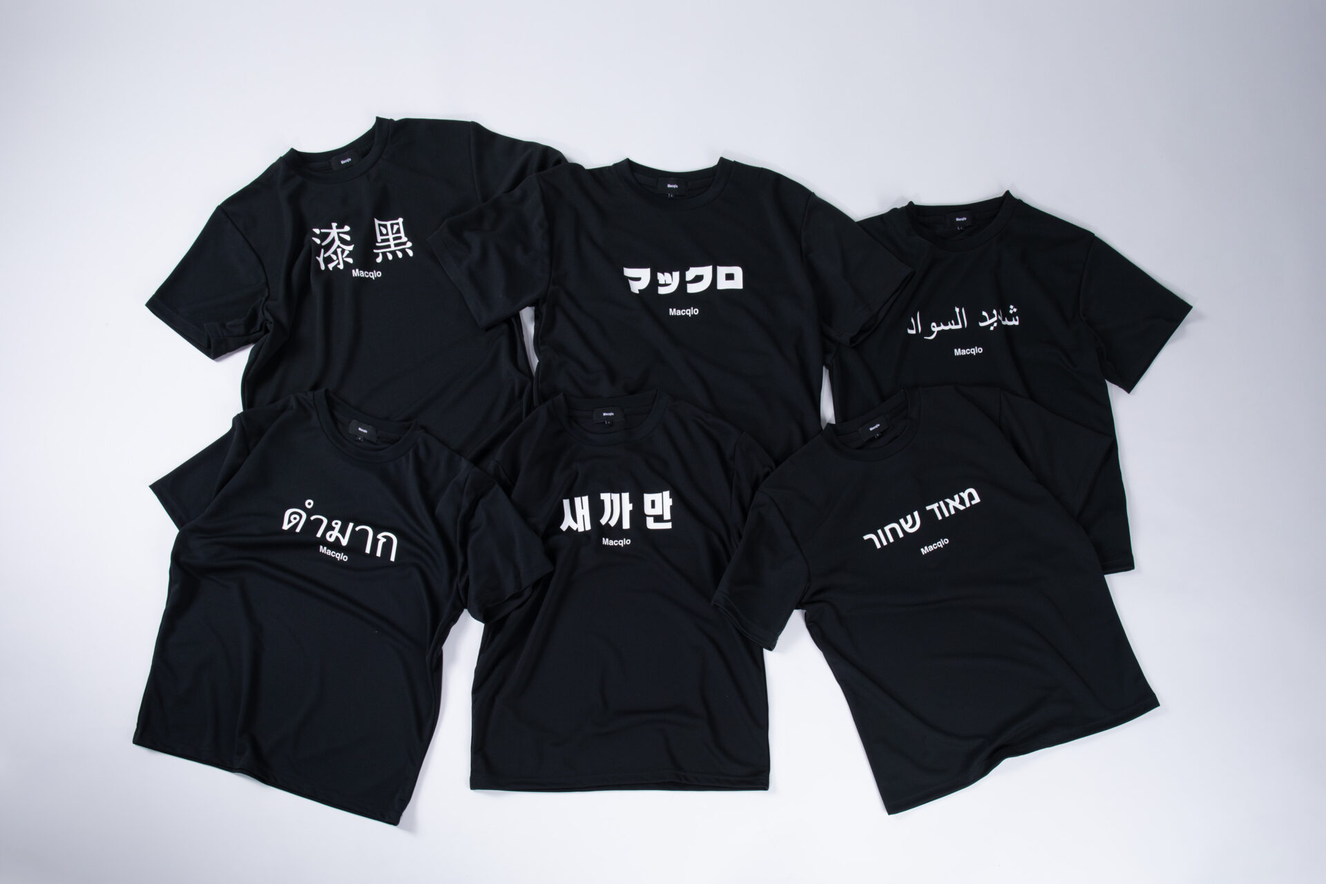 まっくろなハンソデのTシャツに、白の文字で日本語を含む6つのくにの言語で「マックロ」という意味をあらわすたんごがそれぞれ書かれた6種類のTシャツの写真