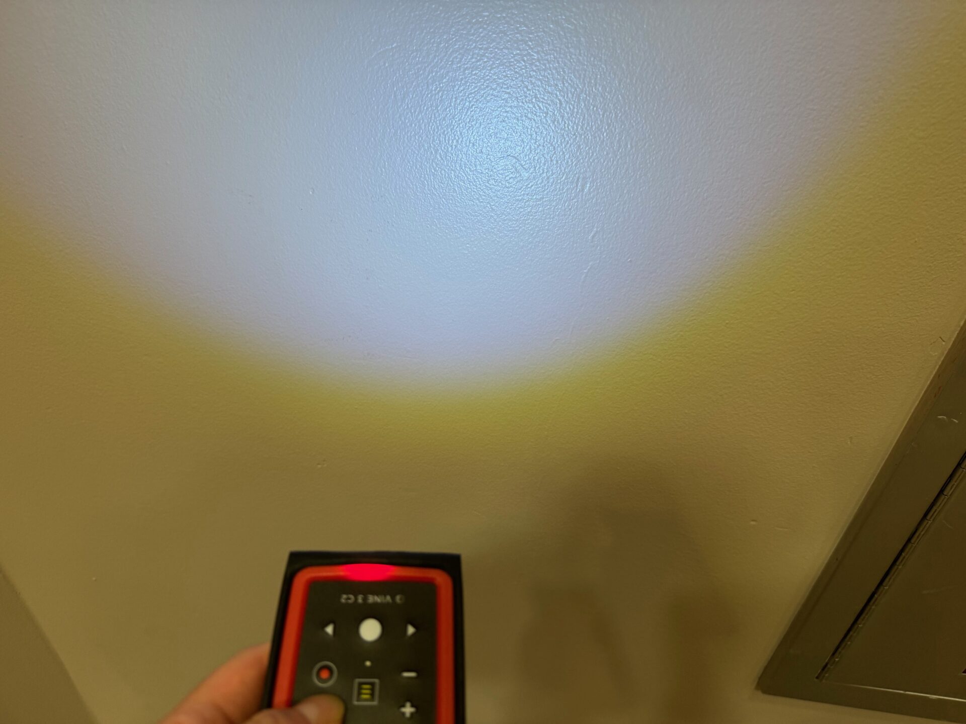 ライトで壁を照らしている様子の写真。本体おもてめんにあるボタンを押すと、本体かぶにあるライトがひかります。けっこう明るい