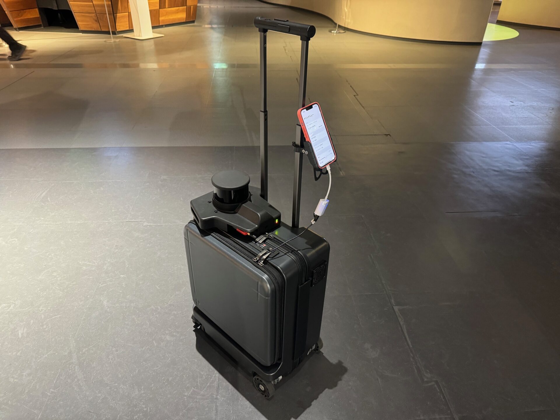 エーアイスーツケースの写真。伸縮ハンドルの部分に専用アプリを搭載したスマホがとりつけられています