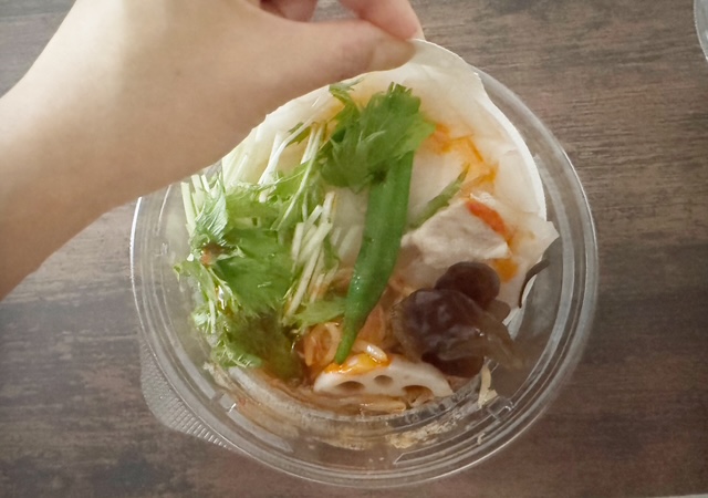 なかざらを左手でひっぱり、そのうえの野菜と麺をスープにまぜようとしている写真。なかざらにわつまみのようなものがついているので、ひっぱりやすいです