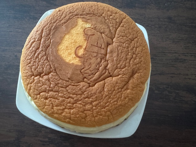 透明なふくろからだした、りくろーおじさんのホールサイズのチーズケーキの写真。てっぺんのりくろーおじさんのやきいんがついた部分は無事だったのですが、そのまわりのちゃいろい部分がぺりっとむけてしまっています