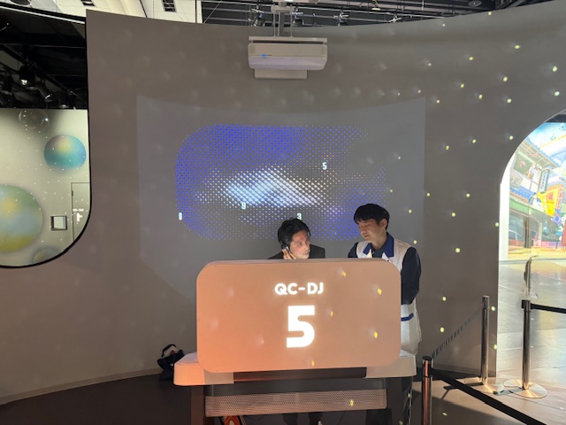 ダンスフロアの写真。遠くにしらとりさんと科学コミュニケーターがいます。しらとりさんはヘッドホンをしていますが、いかにもDJっぽくみえます