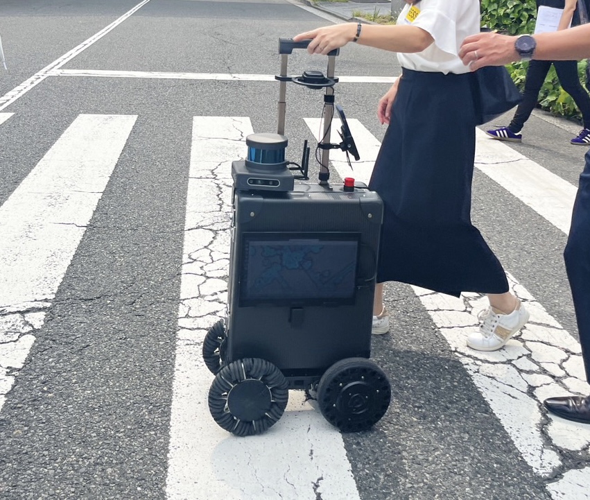 屋外用エーアイスーツケースで誘導してもらいながら歩く女性の写真