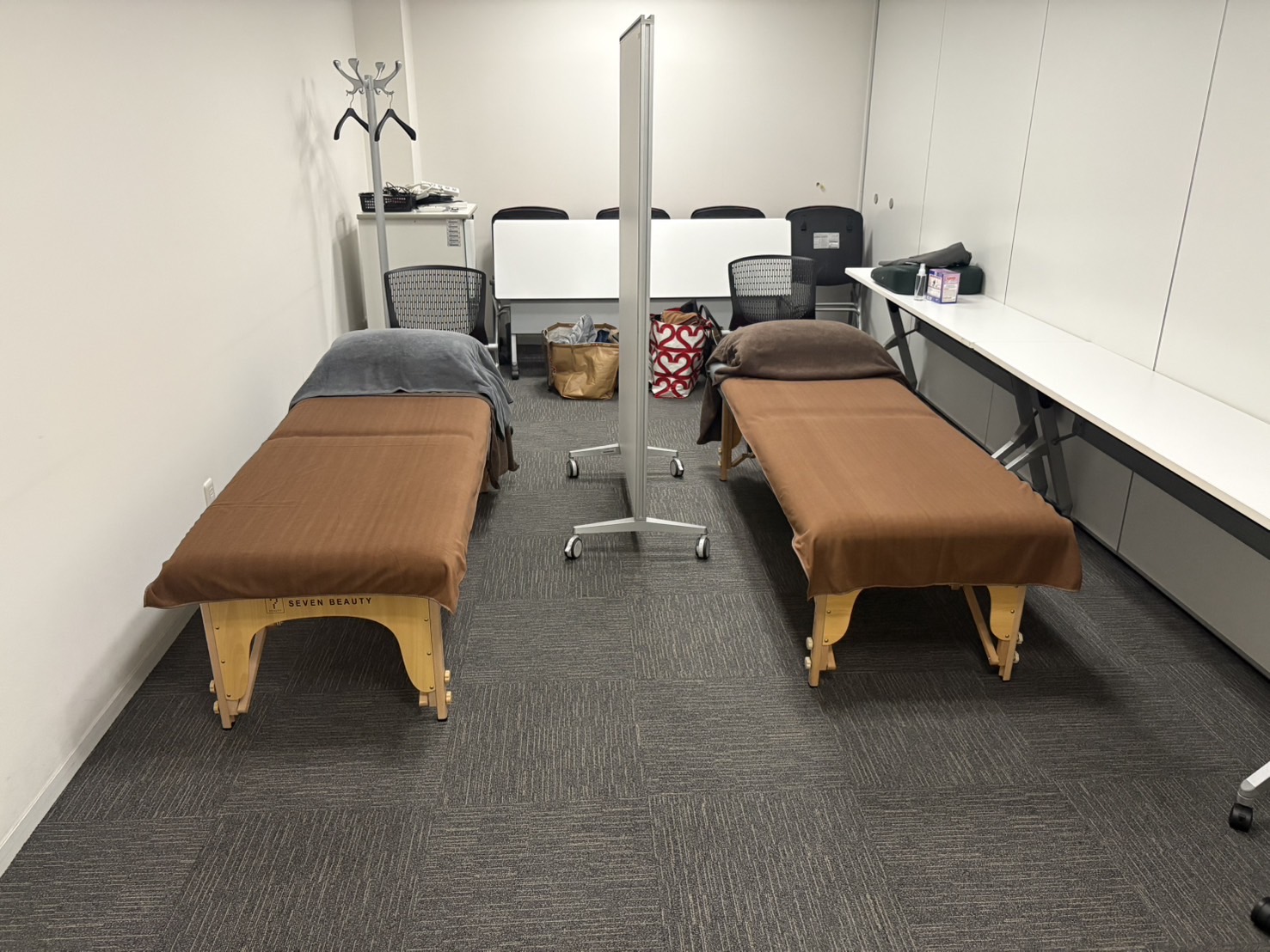 コンパクトな会社の会議室に施術用のベッドが2台おかれている写真