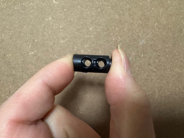 くろいストッパーの両サイドを指でつまむように押さえている写真。ストッパーにわ穴がふたつみえます