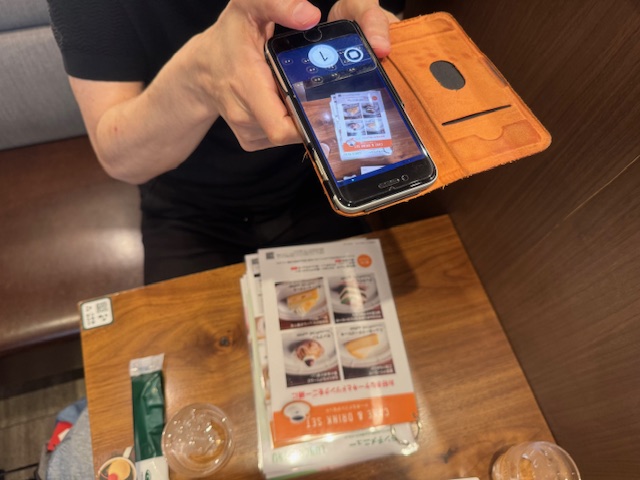 しらとりさんがコーヒーかんのべつのメニューをエンヴィのアプリをとおして撮影している様子をうつした写真
