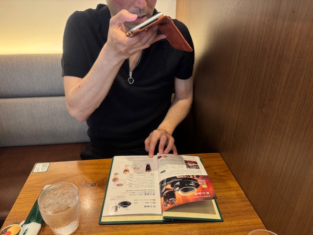 カフェのメニューを撮影し、エンヴィのアプリをとおして会話している視覚障害当事者のしらとりさんの様子を写した写真