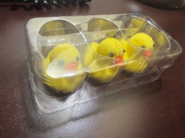 ホテルのつくえのうえにおかれた、パッケージのふくろから出したスリーディーひよこマシュマロの写真。プラスチックのケースにハイっており、蓋までついています