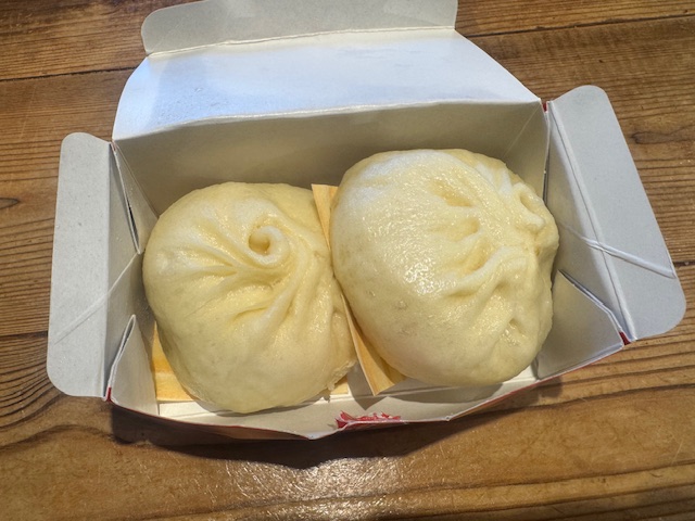 紙製の箱にハイったふたつの肉まん。紙箱のフタを開けるとダイレクトにふたつお目見えします。したについている台紙をハガして食べます