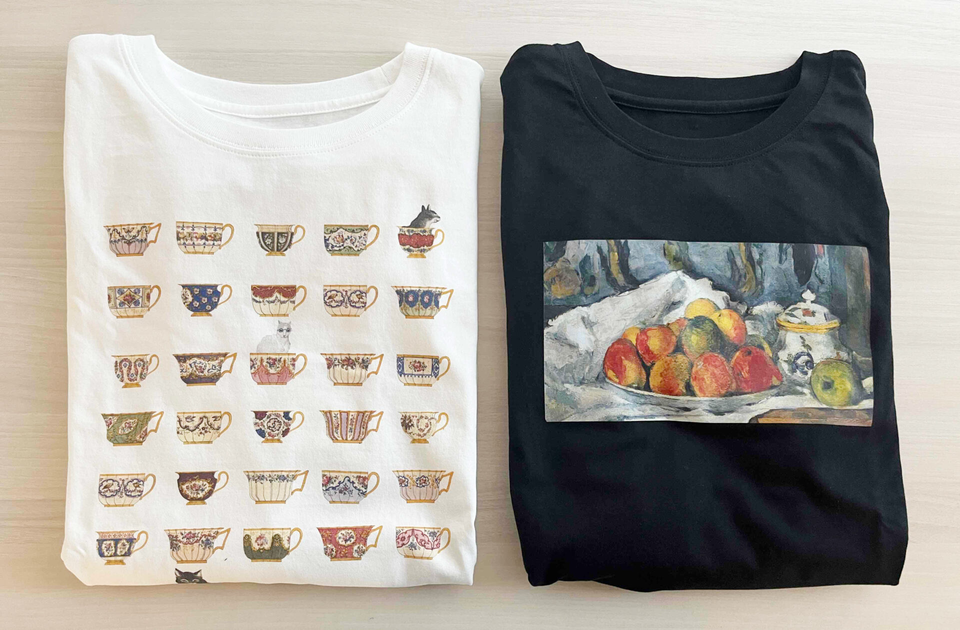 ティーポットの絵柄のしろじのTシャツとリンゴプレートの絵柄のくろじのTシャツが折りたたまれた状態で並べられている写真