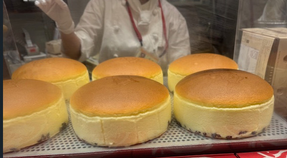 おみせで店員さんがりくろーおじさんのチーズケーキのやきいんをつけたあとの様子の写真。ふわふわ、きいろと茶色の絵本にでてきそうなチーズケーキのてっぺんにやきいんがついた、みためわシンプルなスフレチーズケーキのよう