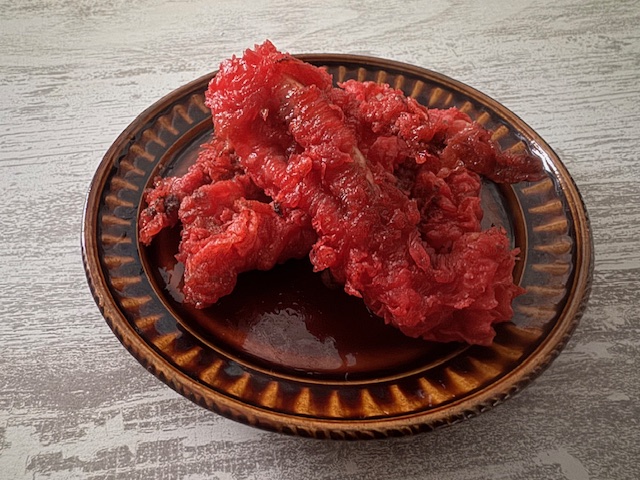 ちゃいろいおさらにのった、ピンクのゲソてんの写真。ころもわピンクというよりどちらかというとあかっぽい、パキットしたいろです