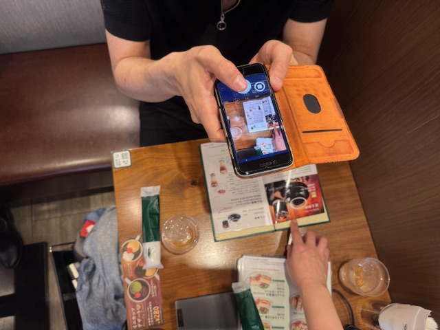しらとりさんがコーヒーかんのメニューをエンヴィのアプリをとおして撮影している様子をうつした写真