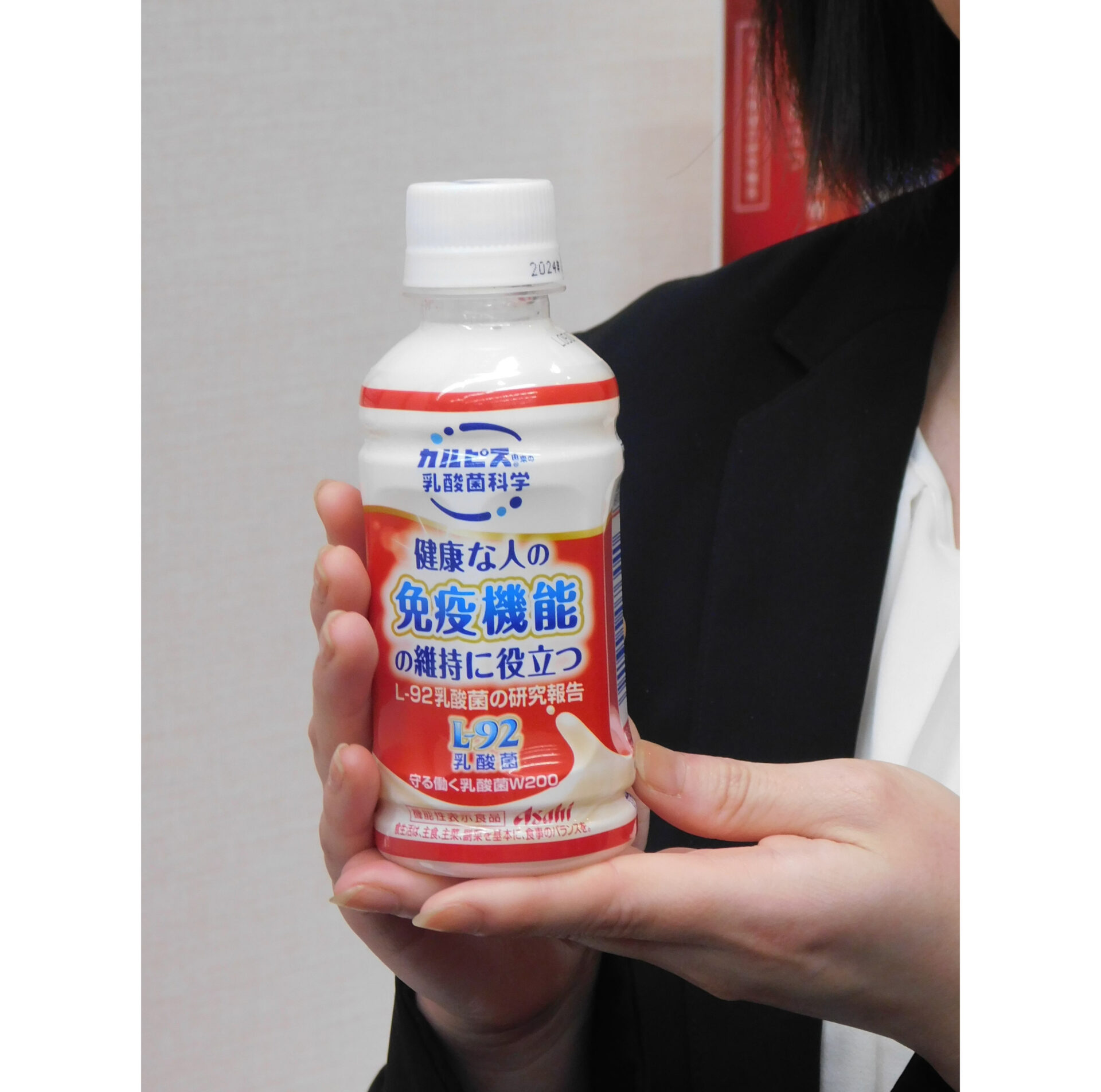アサヒ飲料が６月に発売する機能性表示食品「守る働く乳酸きんW」の商品をもった手元の写真。免疫機能の維持に役立つとしています