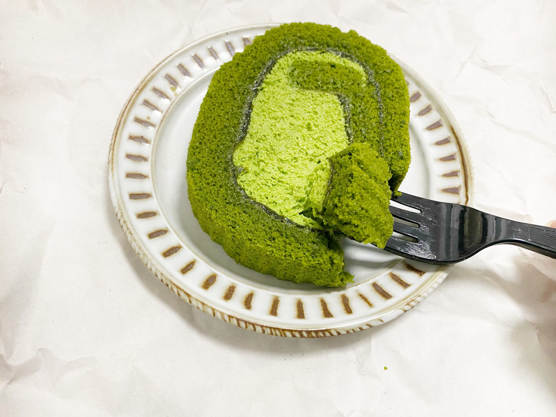 お皿にのった宇治抹茶ロールケーキをフォークですくっている写真