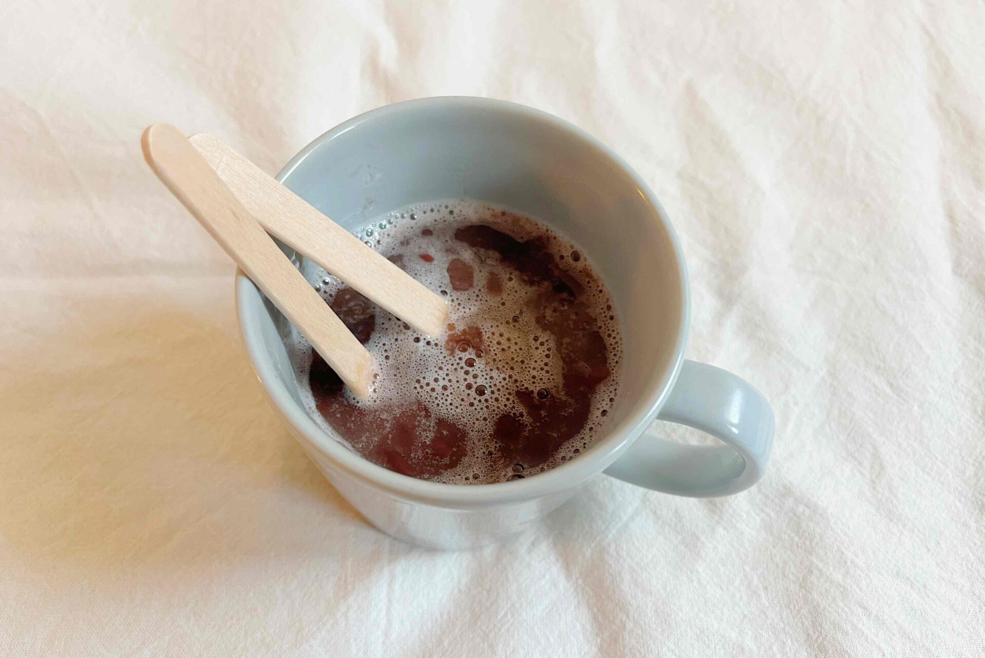 マグカップに溶けたあずきバーが液状になっている写真。スティック2本もそのままハイっています