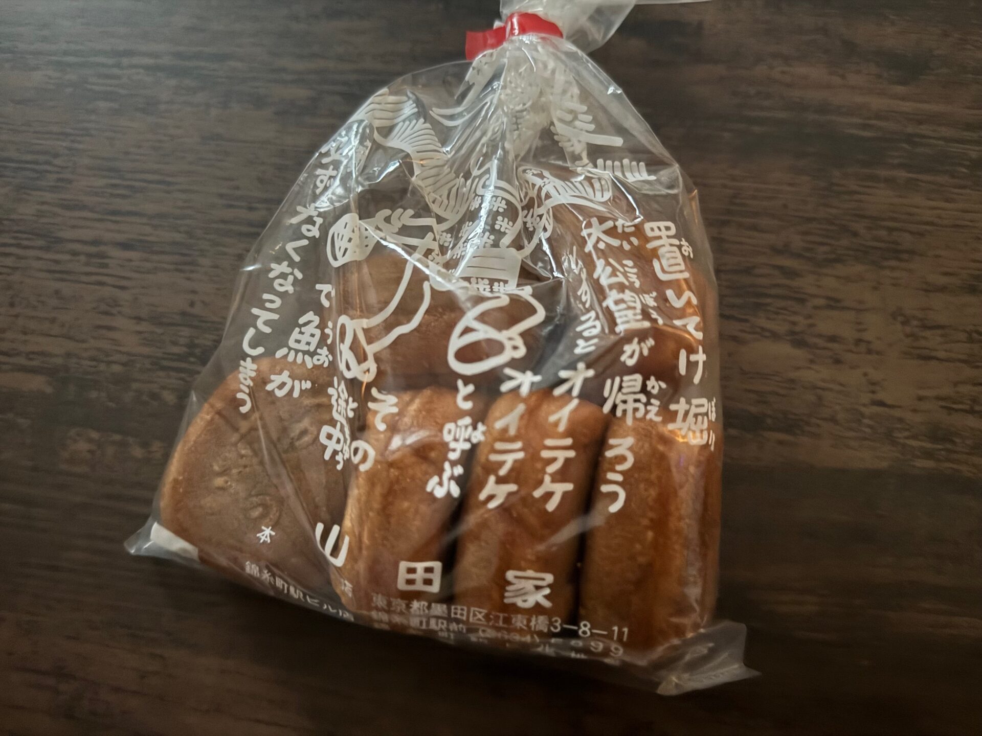 やまだやのにんぎょうやきのパッケージ写真。透明なふくろに白いもじでイラストやテキストなどがえがかれています。こほうそうにわなっていません