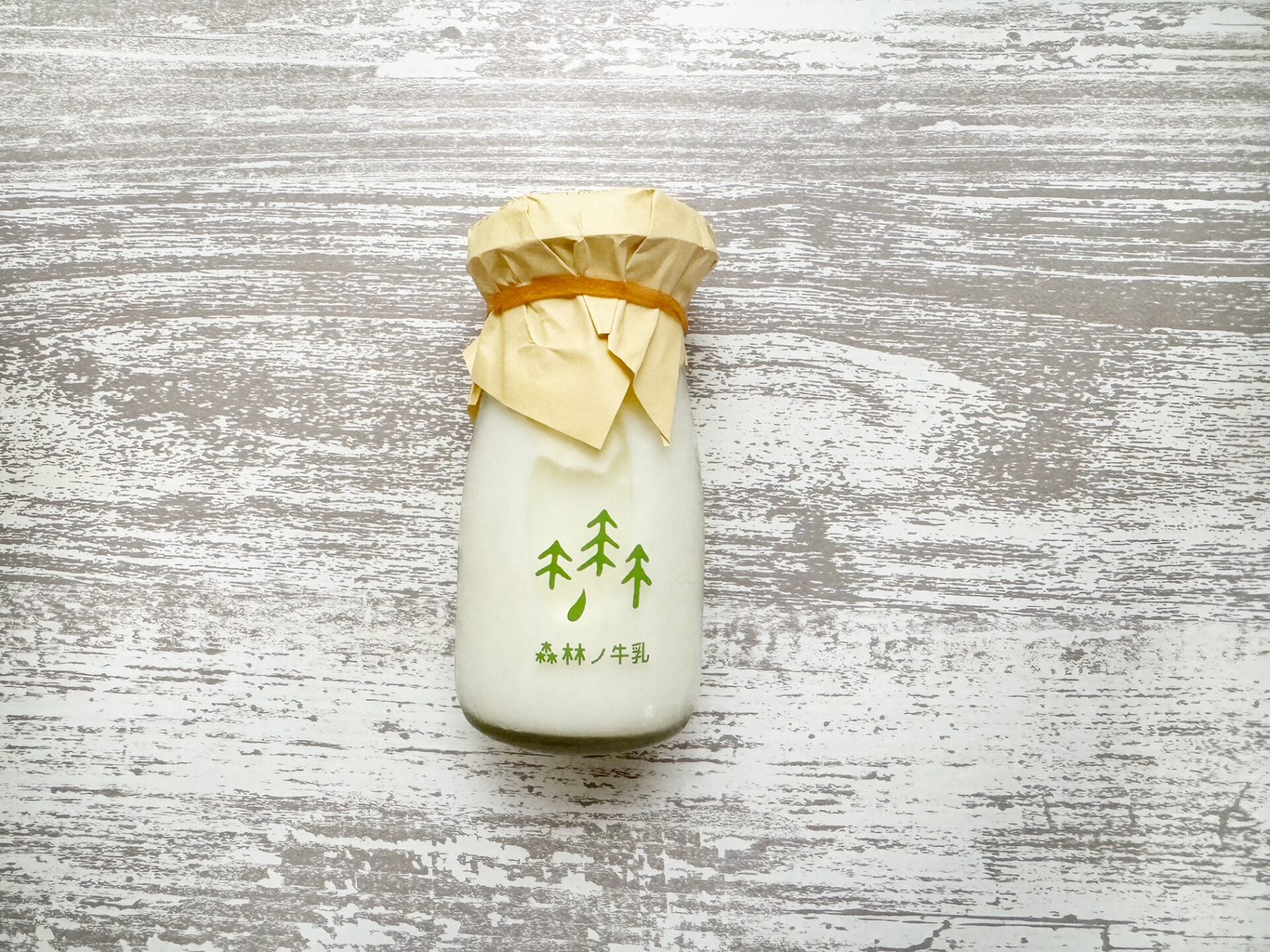 森林ノ牧場 牛乳の商品写真。びんに入っていて、紙の包装をとると、牛乳キャップ、さらにそのしたに紙のフタという構造です。むかしの牛乳瓶のちいさいばんというイメージが近いかもしれません