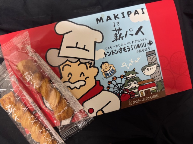 全体が赤っぽい、ひらべったい紙製のハコのまきパイのパッケージと、個包装になったまきパイにほんの写真。こわけのふくろわ手であけられます。パイひとつわ大人の手のひらくらいの大きさです