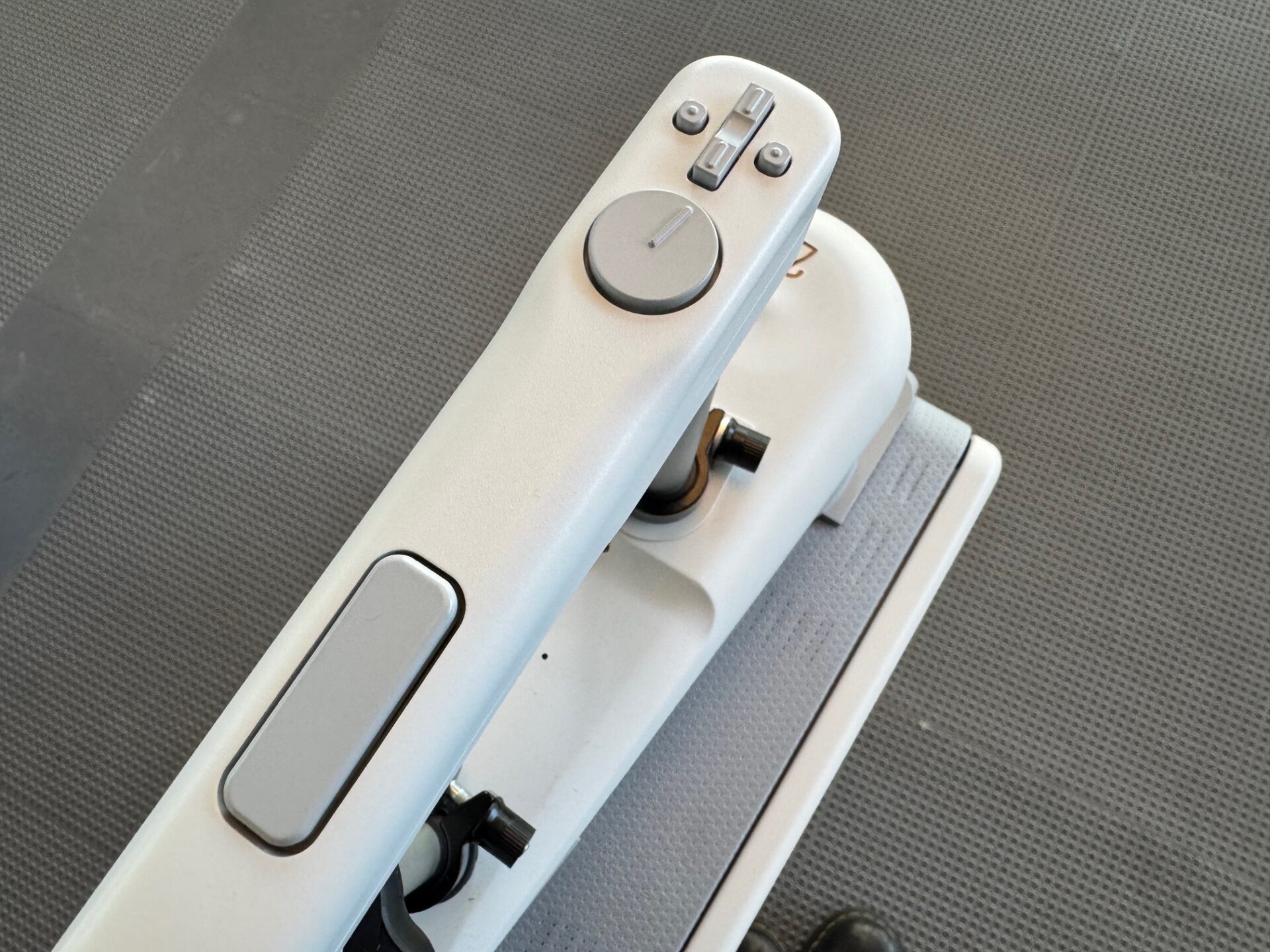 ハンドル部分のクローズアップ写真。ハンドルにたてながのボタンがひとつ、そのりょうサイドにまるいボタンがひとつずつついており、そのしたにディスク型方向提示装置がついています