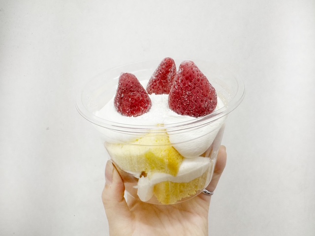 ふんわりシフォンケーキのパッケージをてでもちあげた写真。フタをあけたふんわりクリームシフォンのうえに、くちどけいちごがさんつぶのっています