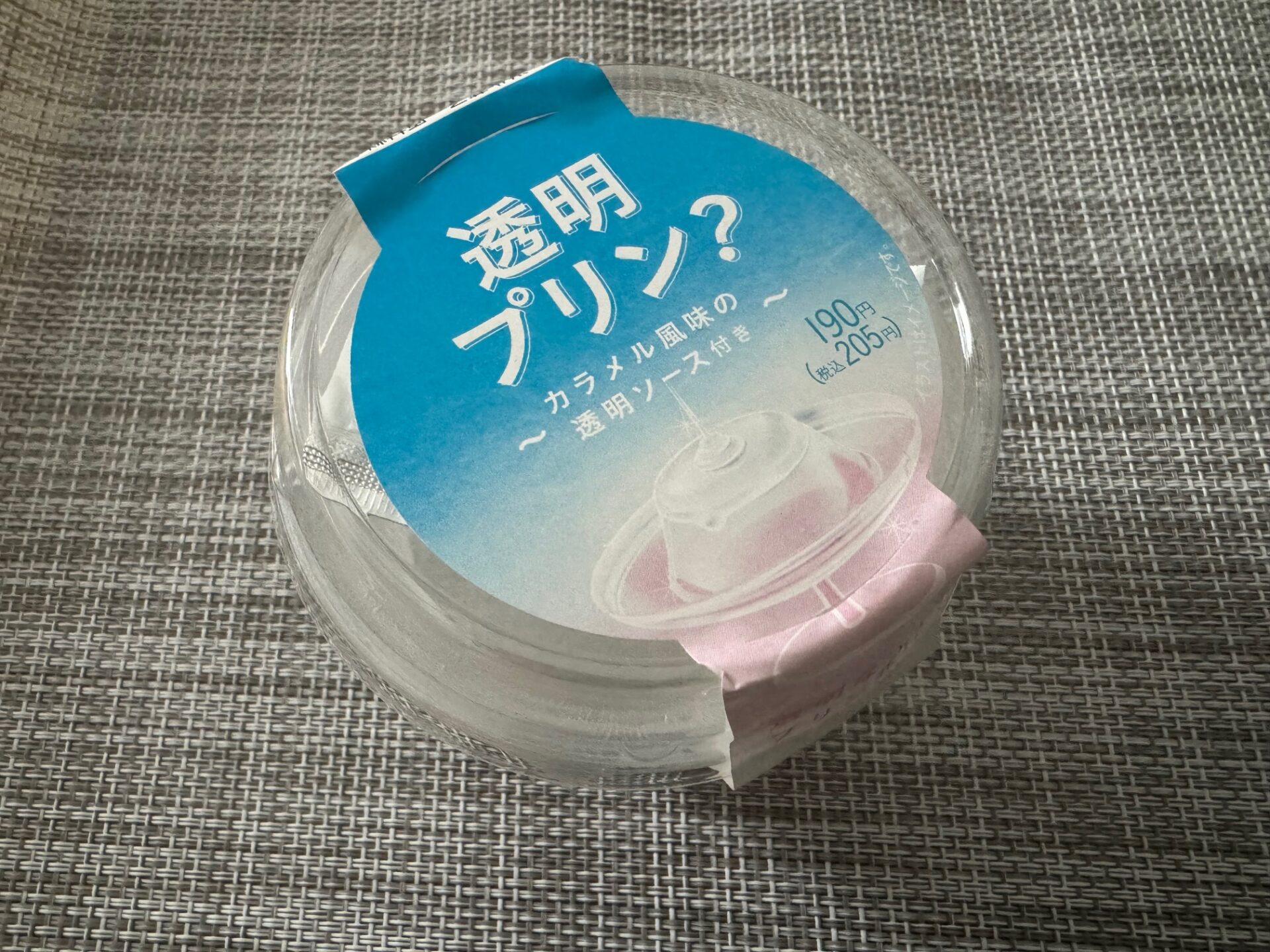 :透明プリンのパッケージの写真。 透明なプリンの容器に、「透明プリン?」とかかれています。パッケージのシールは水色、白、ピンクのグラデーションがかかっていてきれいです