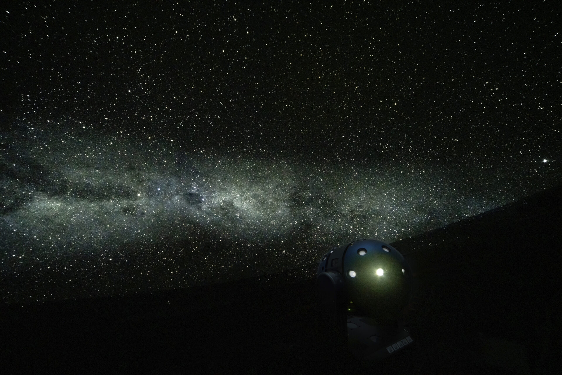 美しい星空がプラネタリウムに映し出されている様子。天の川のような細かい星の集合の横に大きな輝く星が写っている。