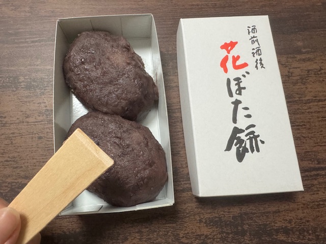 ハコをあけ、木べらとともに写っているハナぼたもちの写真。ハコをあけるとダイレクトにぼたもちがふたつドーンとハイっています。木べらはひとつついていました