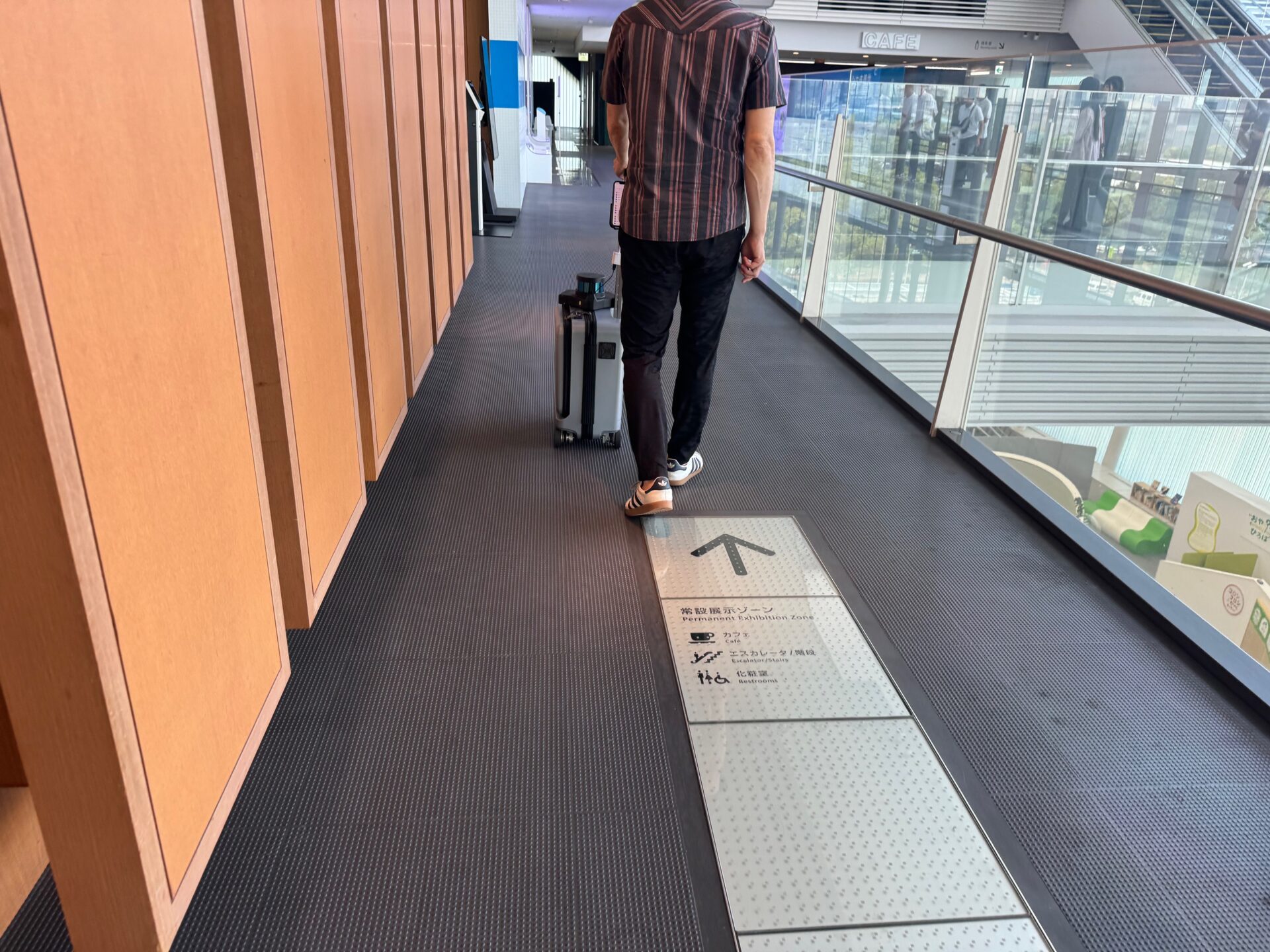 左手にエーアイスーツケースのハンドルをにぎって館内を歩くしらとりさんの写真