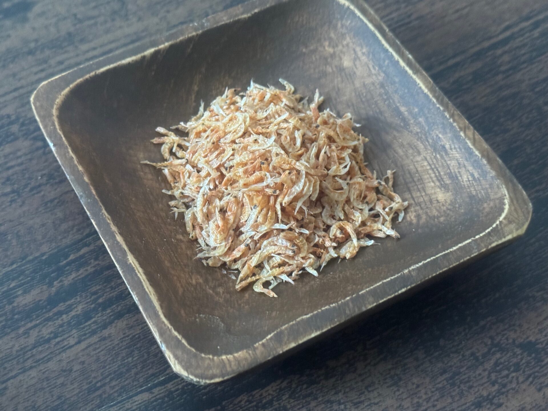 もくせいのしかくいお皿にもりつけられた、おきあみの写真。お皿の茶色とえびのオレンジのコントラストがいい感じです