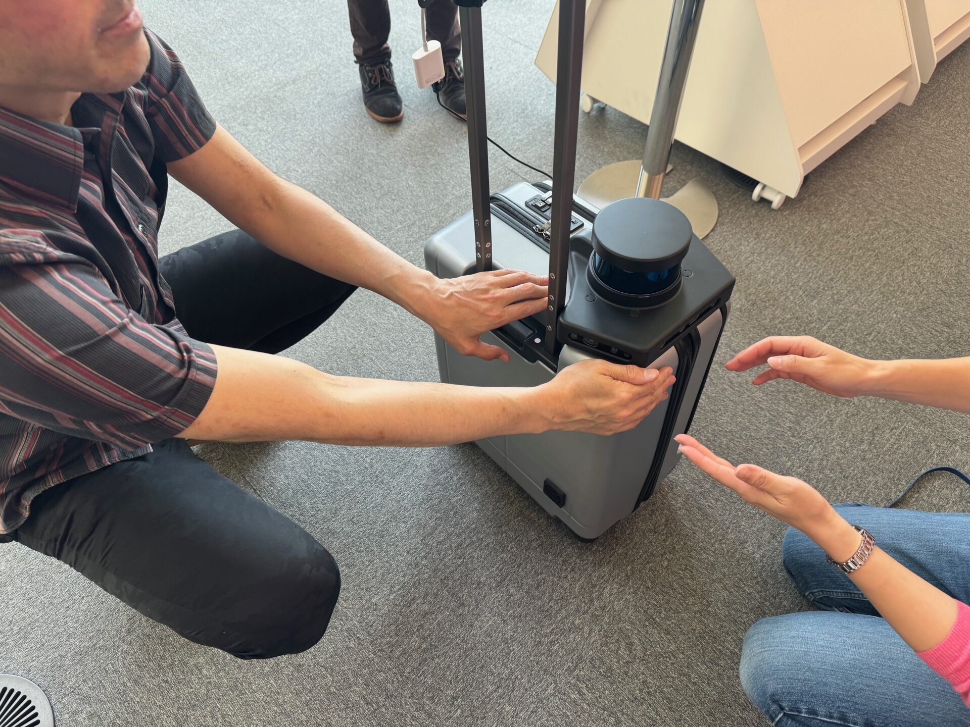 実際にエーアイスーツケースをさわりながら使いかたのレクチャーをうけるしらとりさんとスタッフさんの写真