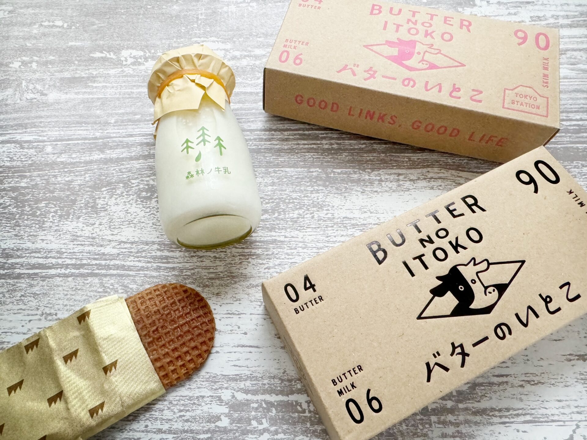 グッドニューストーキョーで買えるバターのいとこの2種類の紙箱のパッケージと、紙のつつみからすこしでたバターのいとこ、森林ノ牧場 牛乳の写真