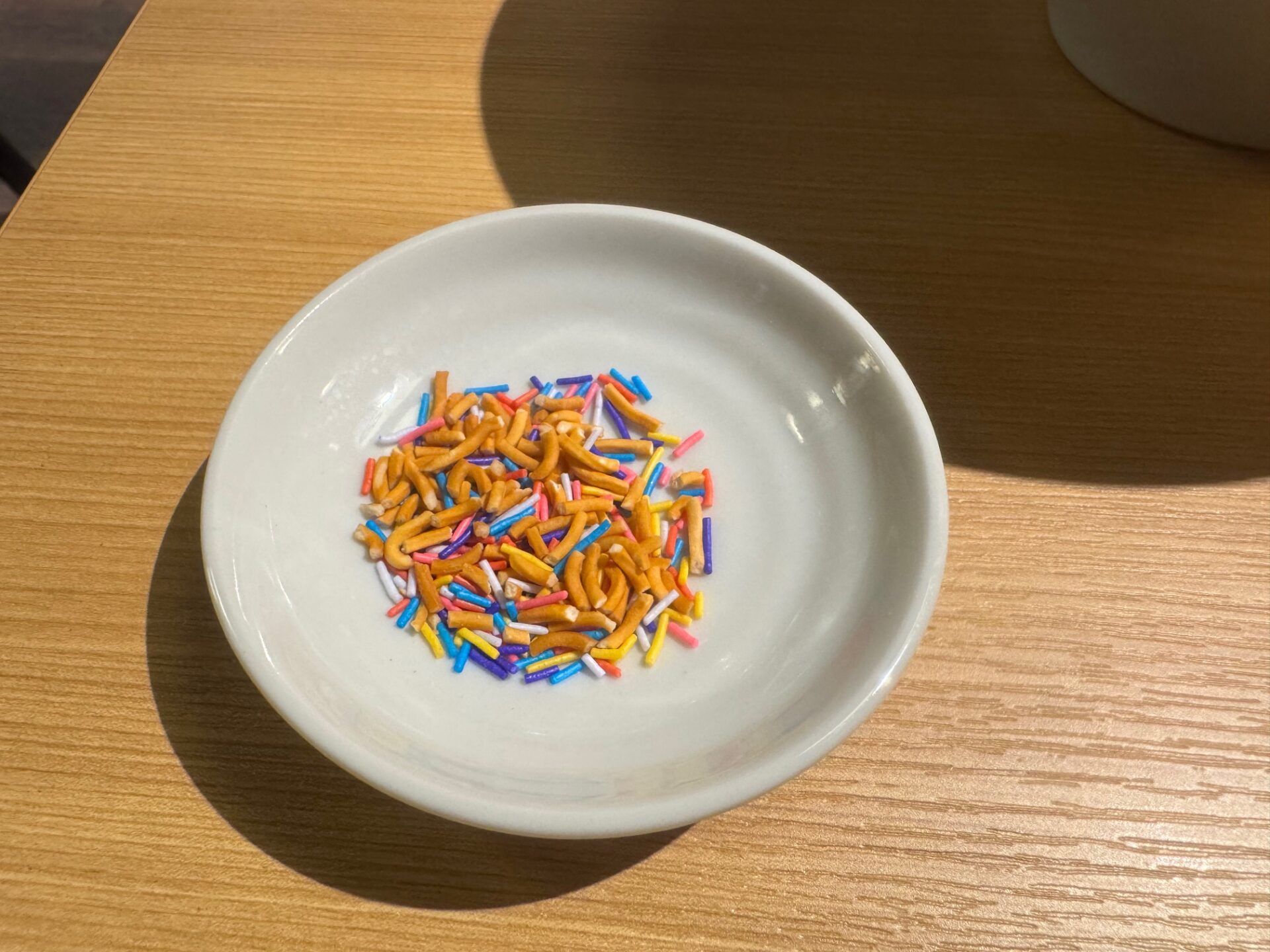 白い小皿にのったトッピングの写真。ベビースターとシュガースプレーにみえます