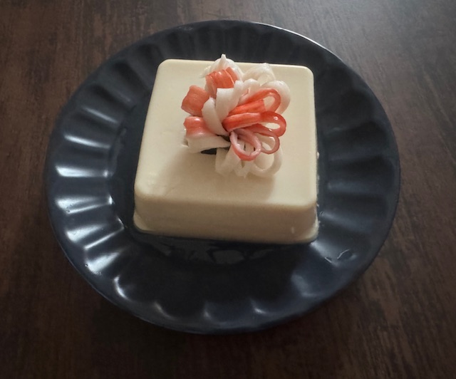 あおいおさらにのった豆腐の写真。豆腐にわカニカマでつくったオハナが凹んだところにのっています